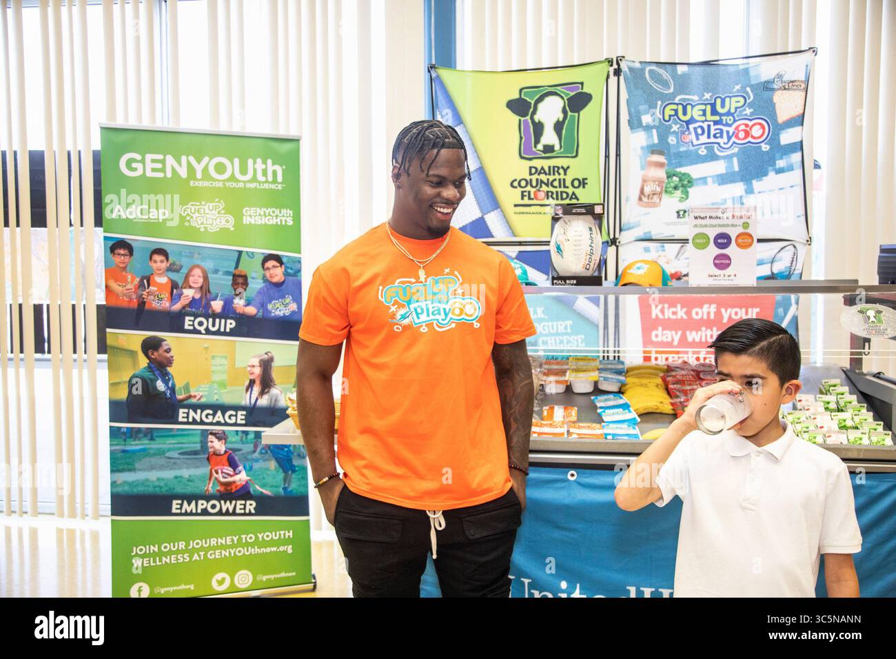 11 mars 2020, West Palm Beach, Floride, États-Unis : pour célébrer le mois national de la nutrition, Jerome Baker, ambassadeur de la marque Fuel Up to Play 60, sourit alors qu’un étudiant de l’école primaire C.O. Taylor/Kirklane de Palm Beach boit un verre de lait le 11 mars. Jerome était présent pour le dévoilement d'un nouveau chariot de petit déjeuner à l'école fourni par GENYOUth et ses partenaires UnitedHealthcare et le Dairy Council of Florida. Grâce à la générosité de UnitedHealthcare, le chariot est l'un des 19 qui sont livrés aux écoles primaires du comté de Palm Beach pour s'assurer que tous les enfants ont accès à un an nutritif Banque D'Images