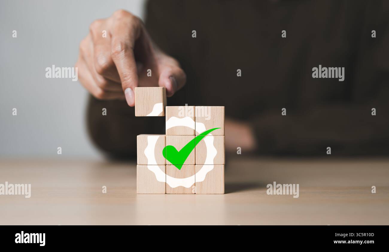 Homme d'affaires a mis à la main cube en bois avec icône de garantie de qualité. Contrôle de qualité et concept standard de certificat. Normalisation des services ISO, qualité AS Banque D'Images