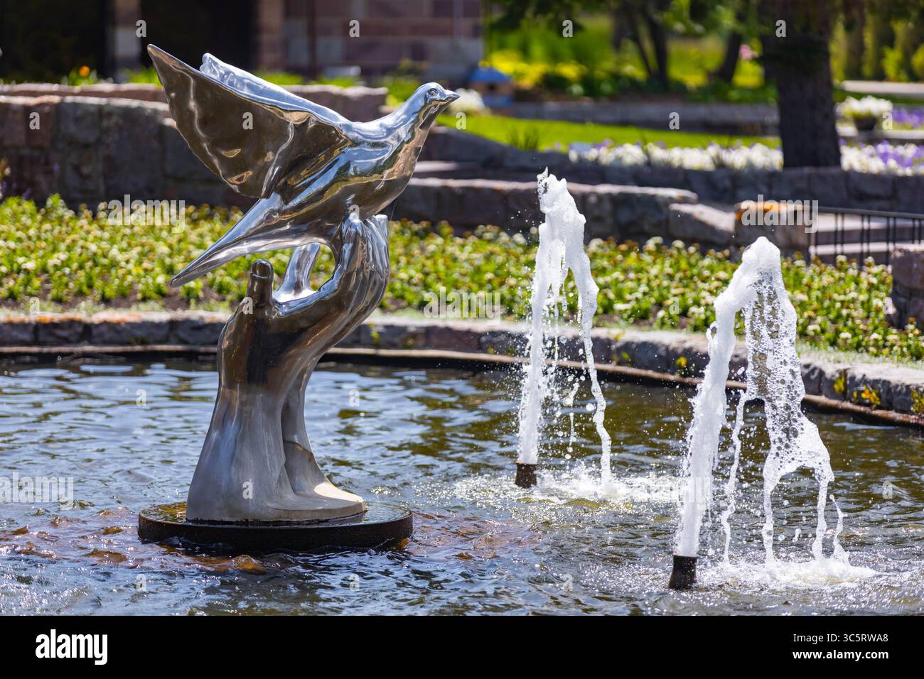 Dunseith, ND, États-Unis - 05 juillet 2025 : une fontaine sereine au jardin international de la paix représente une colombe volant gracieusement de mains Banque D'Images