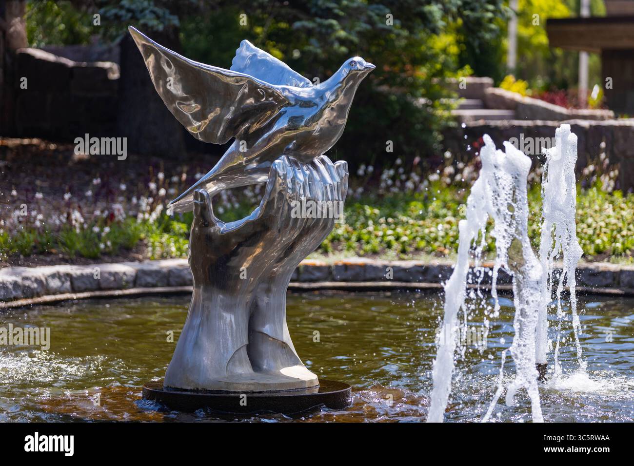 Dunseith, ND, États-Unis - 05 juillet 2025 : une fontaine sereine au jardin international de la paix représente une colombe volant gracieusement de mains Banque D'Images