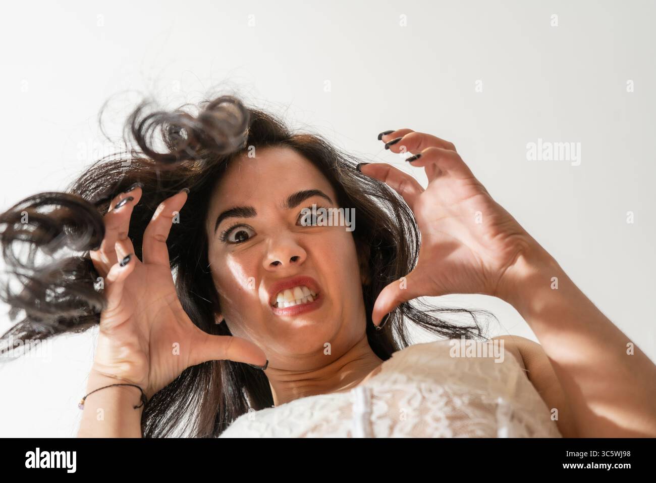 Jeune femme exprimant la rage et la fureur, les mains griffées et les cheveux désalignés, représentant un stress émotionnel intense Banque D'Images
