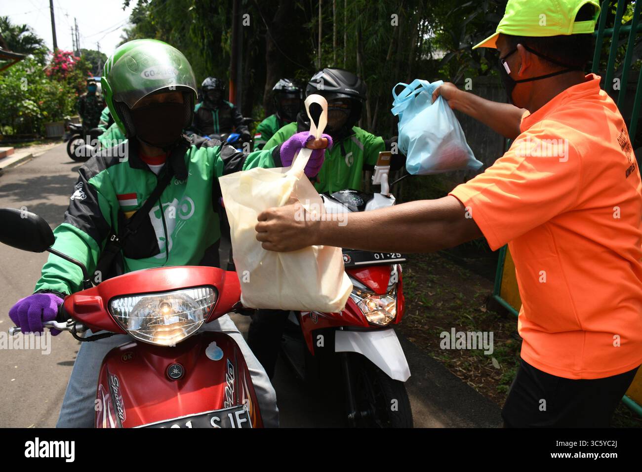 5 septembre 2019, Cipayung, Jakarta, Indonésie : des volontaires donnent des colis alimentaires aux chauffeurs de moto-taxi en ligne dans la région de Cipayung, Jakarta, le 18 avril 2020. Pas moins de 200 colis alimentaires ont été distribués en ligne aux chauffeurs de motos-taxis, car depuis que la co-pandémie a eu lieu en Indonésie, leurs revenus ont diminué. Depuis les nombreuses commandes précédentes pour le transport, les utilisateurs utilisent maintenant des chauffeurs pour commander de la nourriture, magasiner pour les nécessités quotidiennes ou livrer des marchandises. (Crédit image : © Dasril Roszandi/ZUMA Wire) Banque D'Images