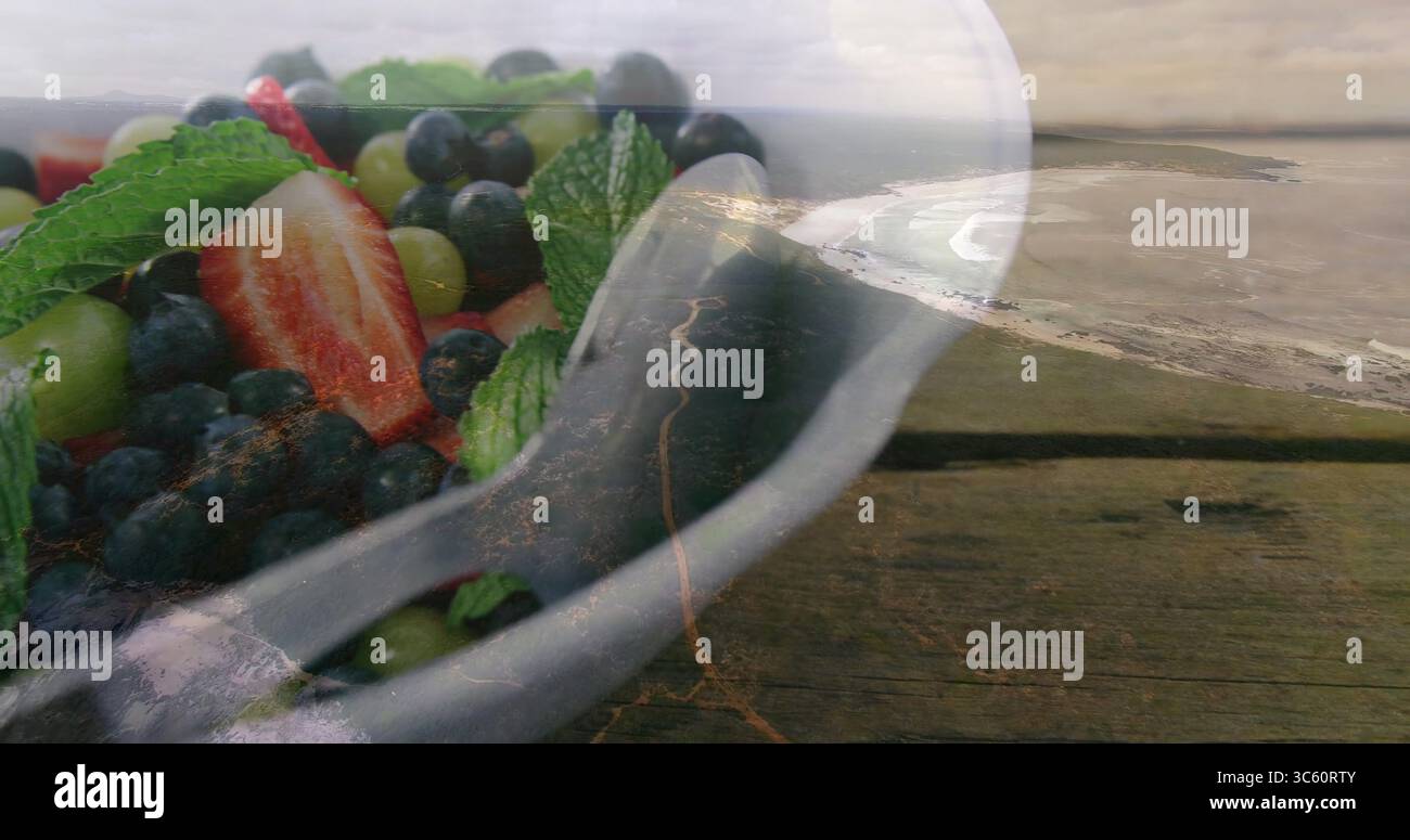 Affichage bol en céramique de raisins et de baies à la menthe sur table surplombant la côte, espace de copie Banque D'Images