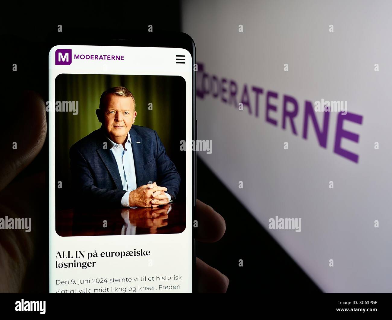 Dans cette illustration photo, une personne tient un téléphone portable avec la page Web du parti politique danois moderne (M) sur l'écran devant le logo. Banque D'Images