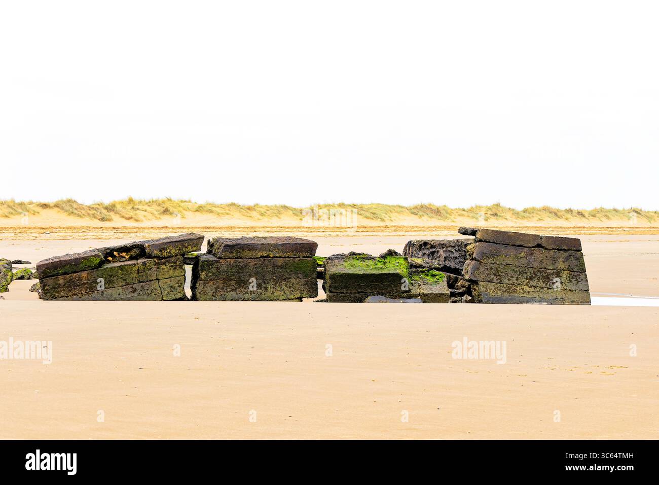 Une grande structure en béton brisée gisant sur les vastes sables de marée Banque D'Images