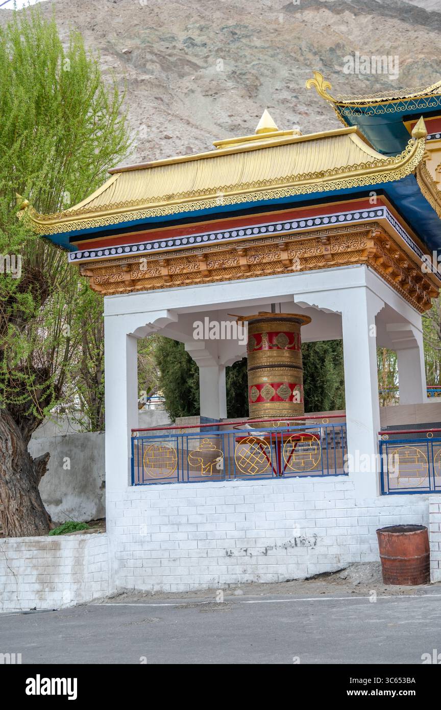 Roue à prières bouddhiste traditionnelle à l'extérieur d'un monastère, symbole de foi et de spiritualité, utilisée pour la méditation et le chant de mantras. Banque D'Images