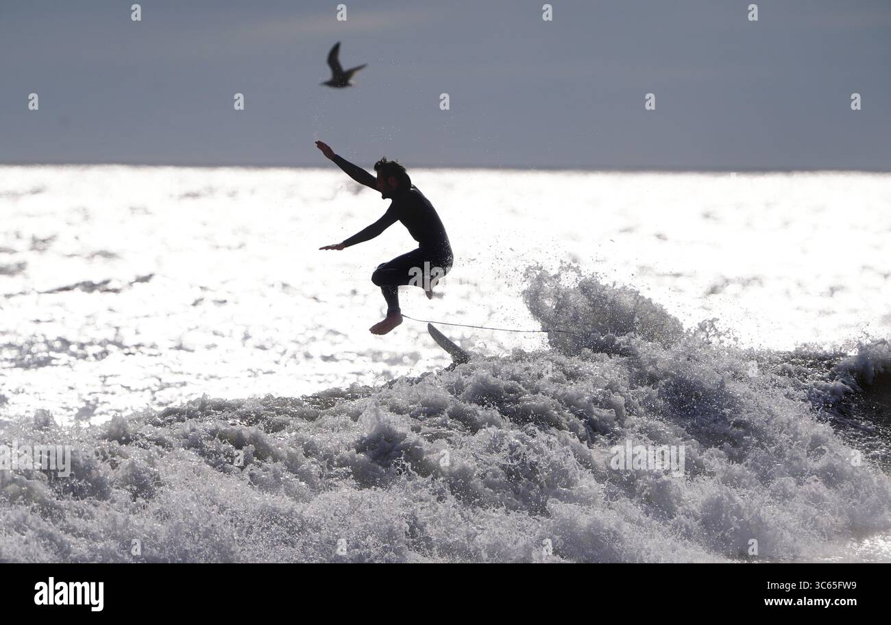 Surfeurs à la plage de Tynemouth Longsands sur la côte nord-est. Date de la photo : jeudi 31 juillet 2025. Banque D'Images