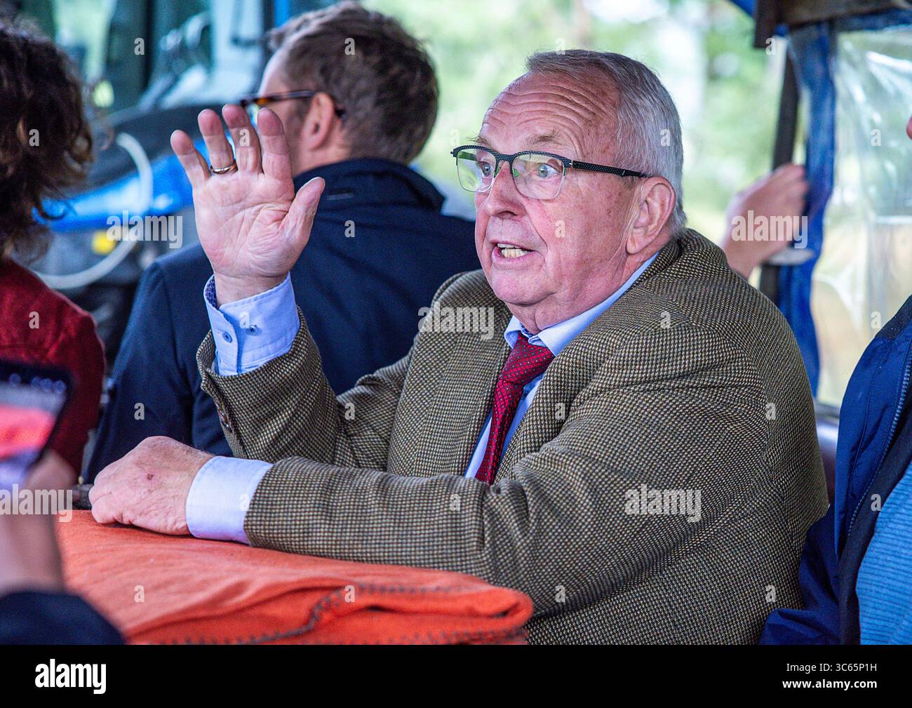 Gorlosen, Allemagne. 31 juillet 2025. Till Backhaus (SPD), le ministre de l'Agriculture, de l'environnement et de la protection du climat de Mecklembourg-Poméranie occidentale, monte sur une remorque du Kremser dans le cadre de sa tournée estivale et découvre sur place le projet « conservation des Moors avec des buffles d'eau ». Un troupeau de 120 animaux est actuellement en mouvement dans les zones où le remouillage des landes doit être mis en œuvre. Crédit : Jens Büttner/dpa/Alamy Live News Banque D'Images