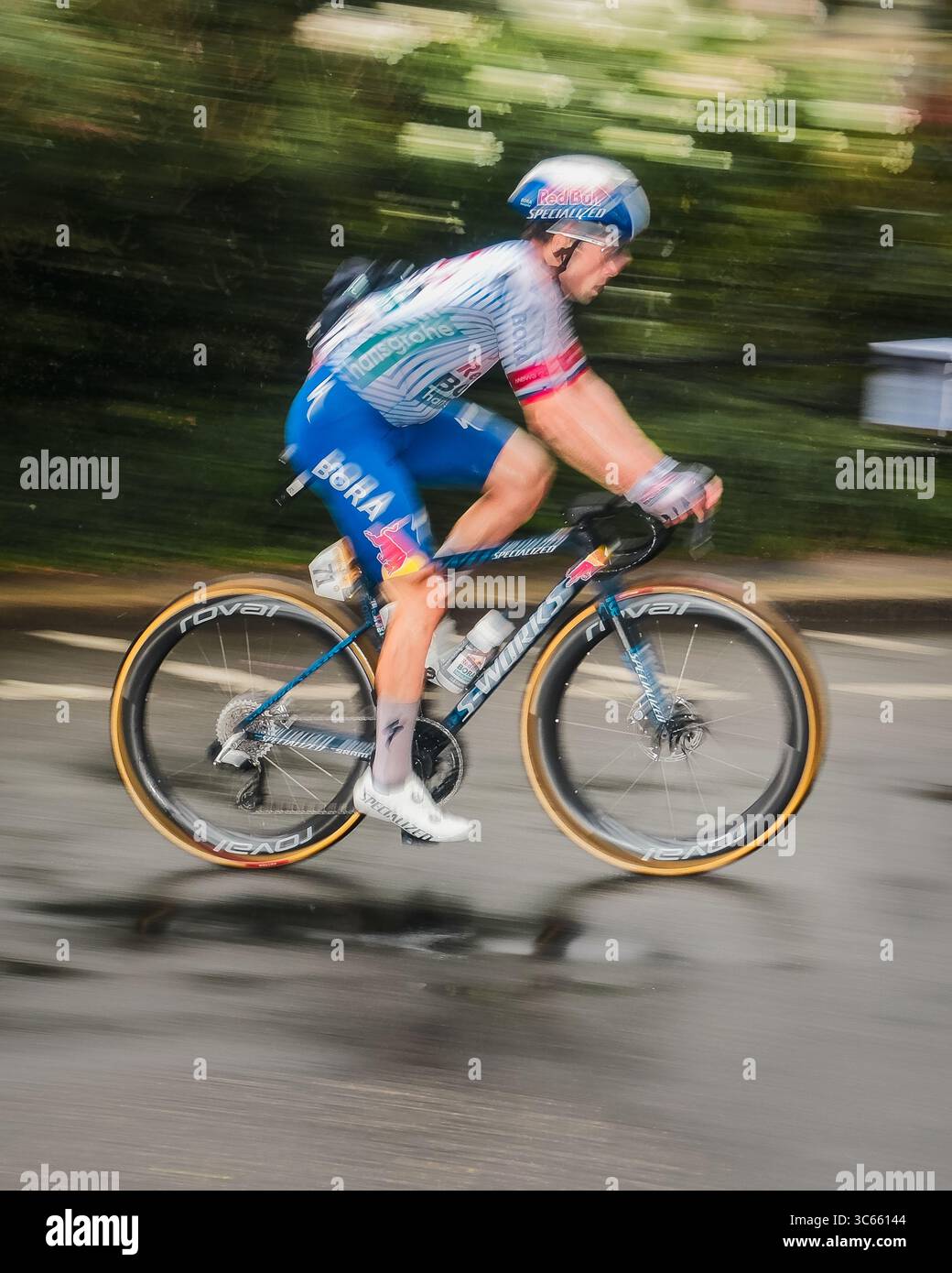 Paris, France - 27 juillet 2025 : vue d'un cycliste du Tour de France 2025 en vitesse sur les routes mouillées, flou de mouvement et de couleurs sur fond de ville. Banque D'Images
