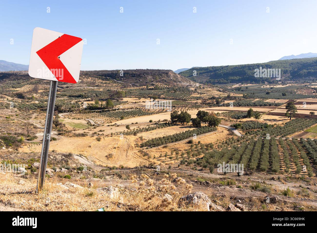 Panneau de signalisation indique à gauche dans la route de la vallée près des champs de ferme, Mugla, Turquie Banque D'Images