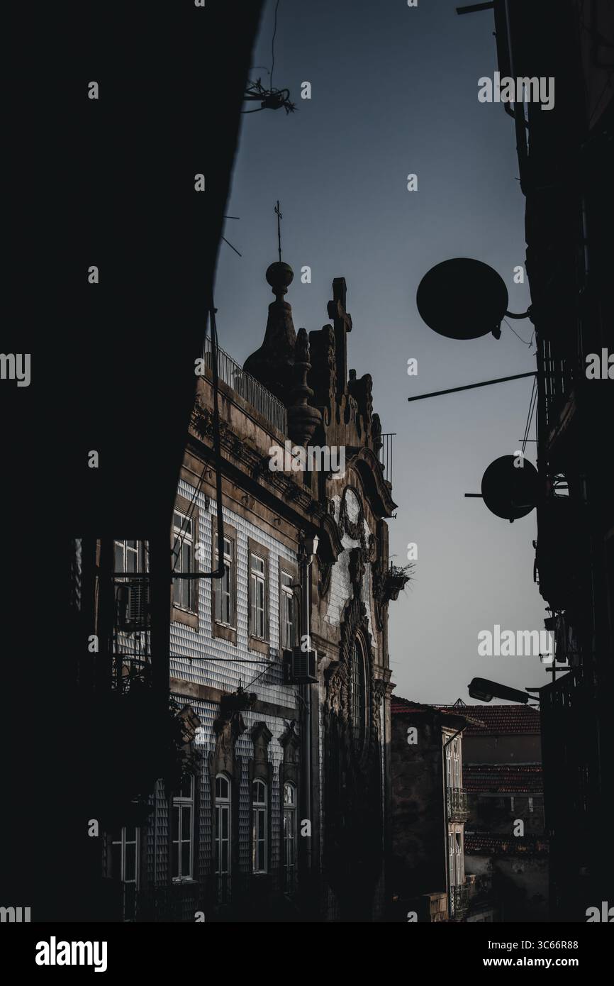 Porto, Portugal - 17 juin 2022 : vue d'un bâtiment historique encadré d'ombres sombres, sa façade ornée témoigne du passage du temps. Banque D'Images