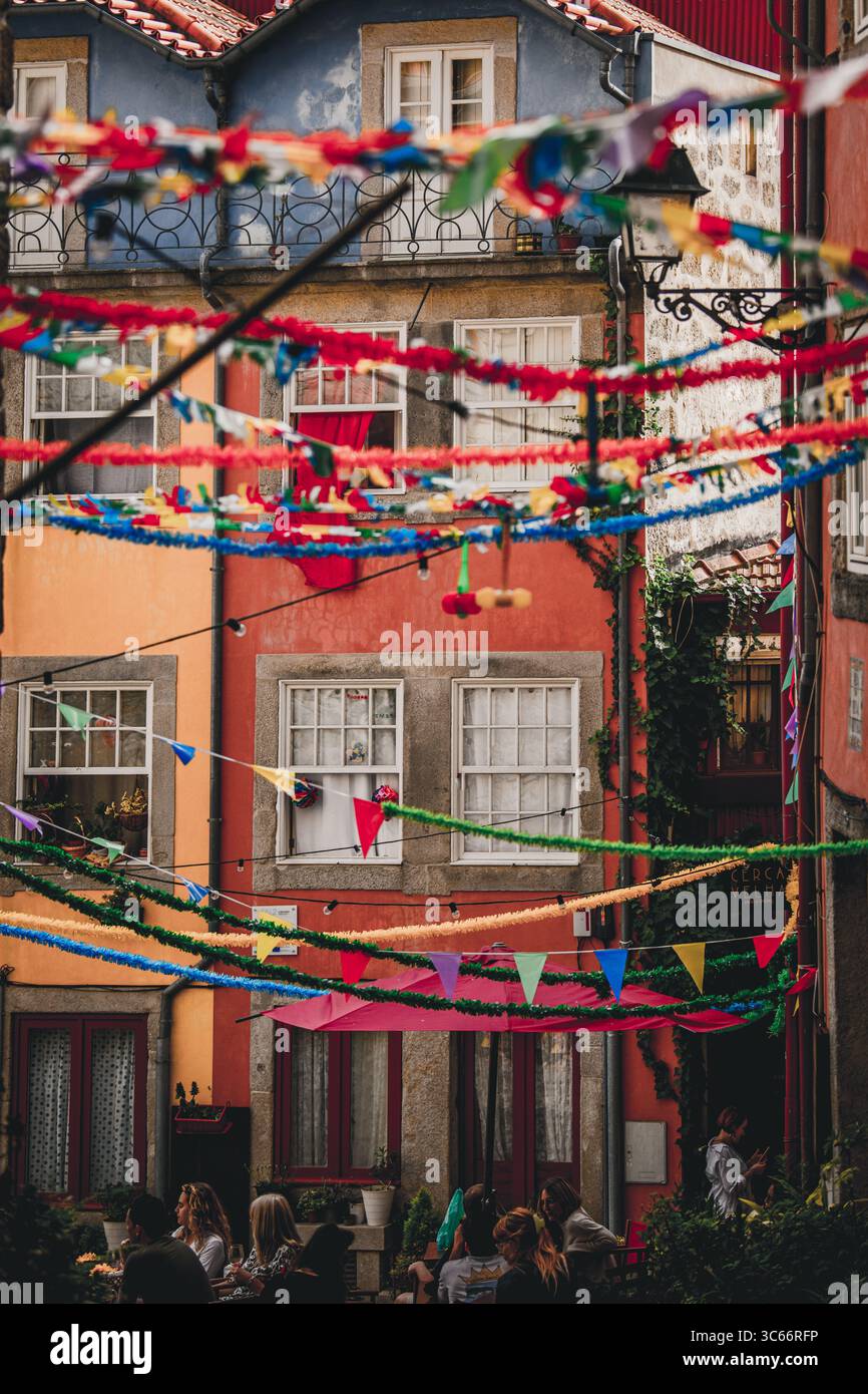 Porto, Portugal - 17 juin 2022 : vue sur des bâtiments vibrants ornés de banderoles colorées, projetant des ombres sur la rue animée ci-dessous. Banque D'Images