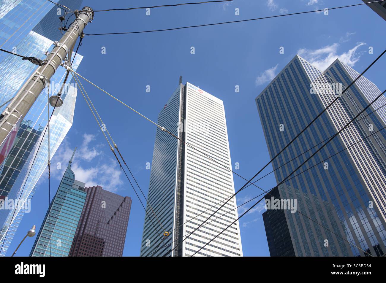 La tour blanche BMO s'élève au centre d'un groupe de gratte-ciel du centre-ville, encadrée par des lignes électriques et un ciel bleu vif. Banque D'Images