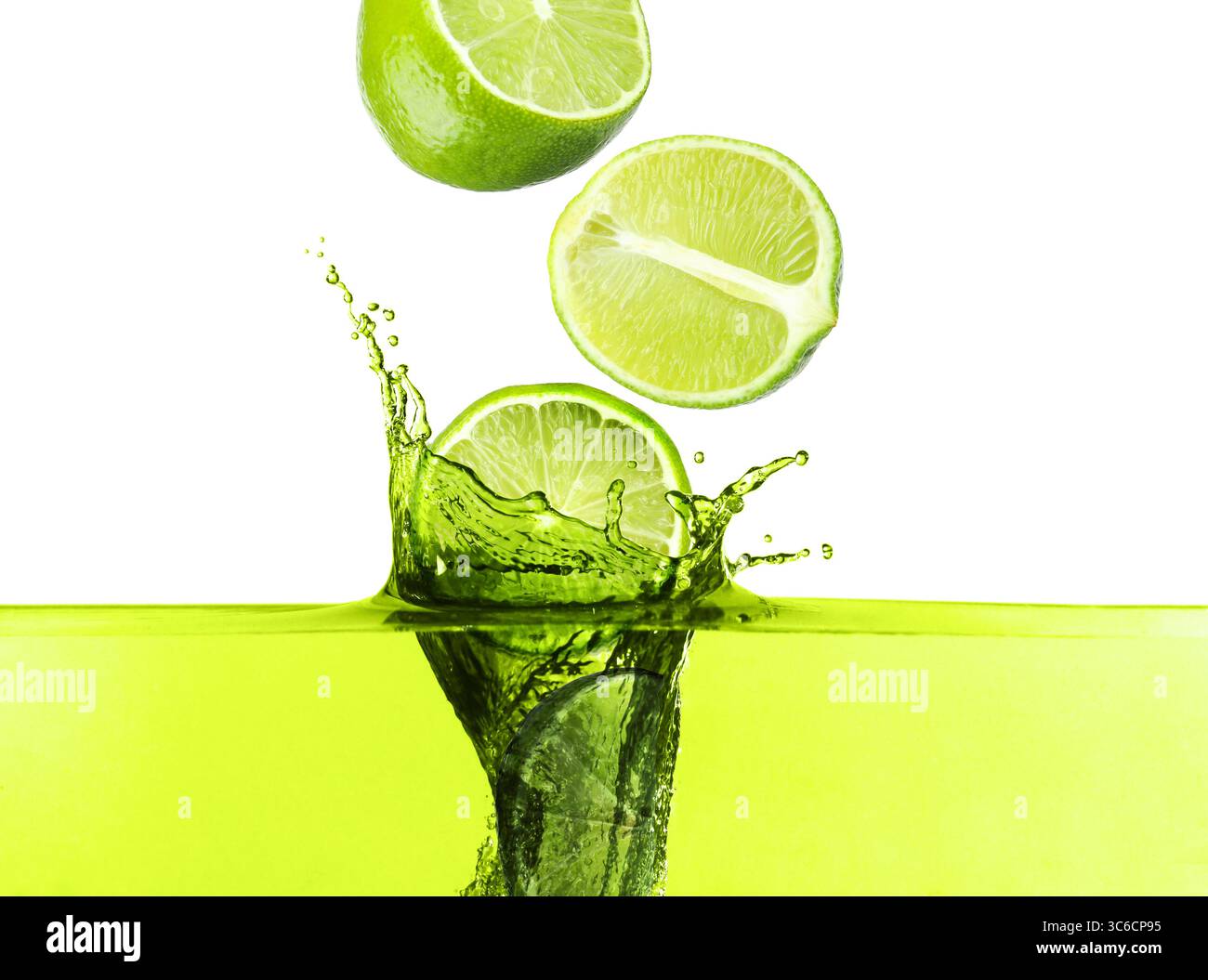 Citrons verts frais tombant dans la boisson éclaboussante sur fond blanc Banque D'Images