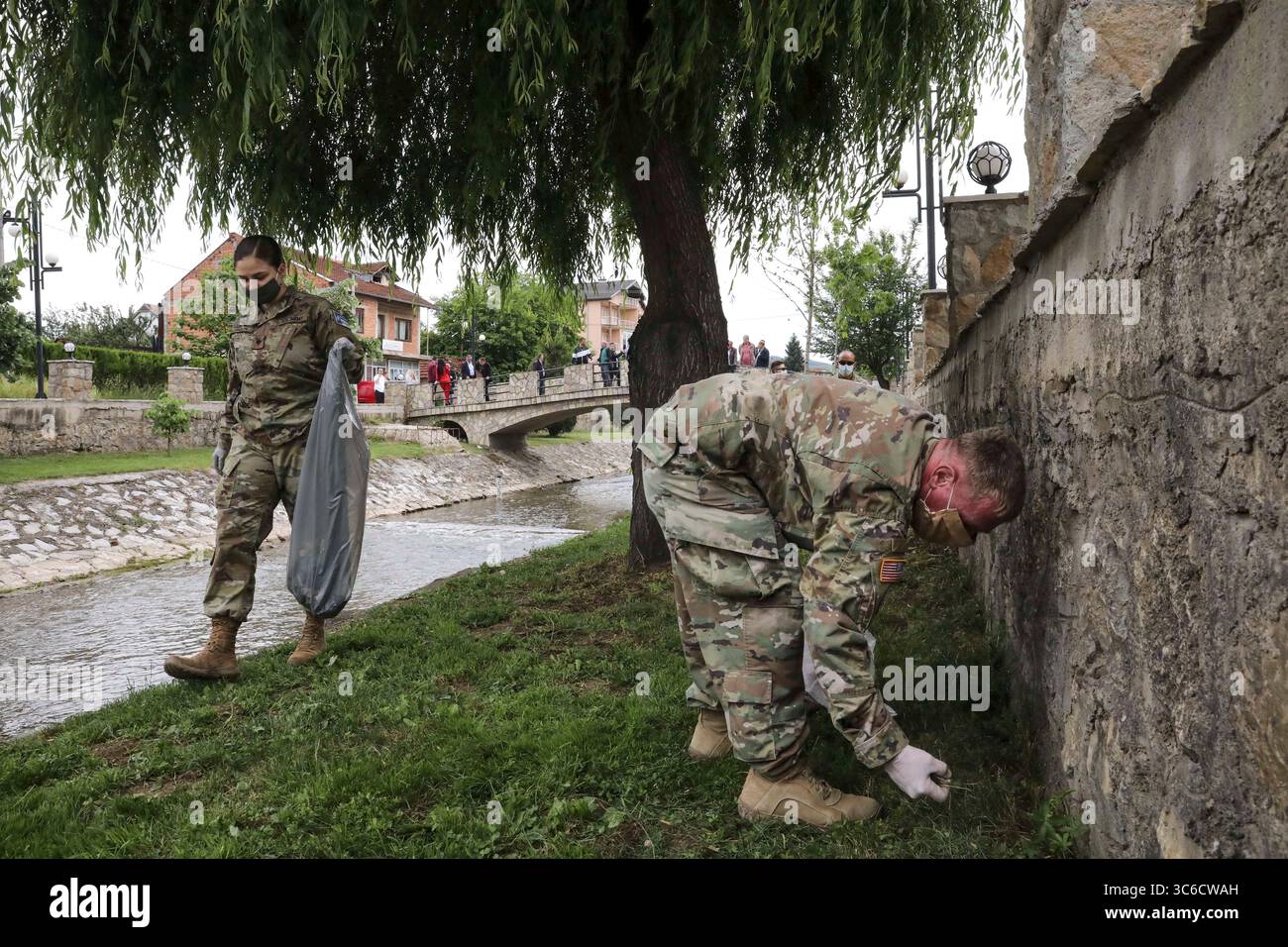 Le 5 juin 2020 - Vitina/Viti (Kosovo) - la SPC Jamie Harrison et le Sgt Aaron Crane de l'équipe de surveillance de liaison est du Commandement régional de la Force du Kosovo Kilo 20â ramassent des ordures le long d'un ruisseau de Vitina/Viti (Kosovo) le 5 juin 2020. Le personnel du LMT du Kilo 20â hors du camp Bondsteel et le personnel du bataillon de manœuvre hors du camp Nothing Hill ont participé à l'embellissement de la zone en observation de la Journée mondiale de l'environnement. Le maire de cityâs, Sokol Haliti, invita les soldats de la RC-E à planter des fleurs et un arbre et à peindre un amphithéâtre sur la place de la ville et ramasser les ordures dans un ruisseau voisin avec le personnel de Banque D'Images