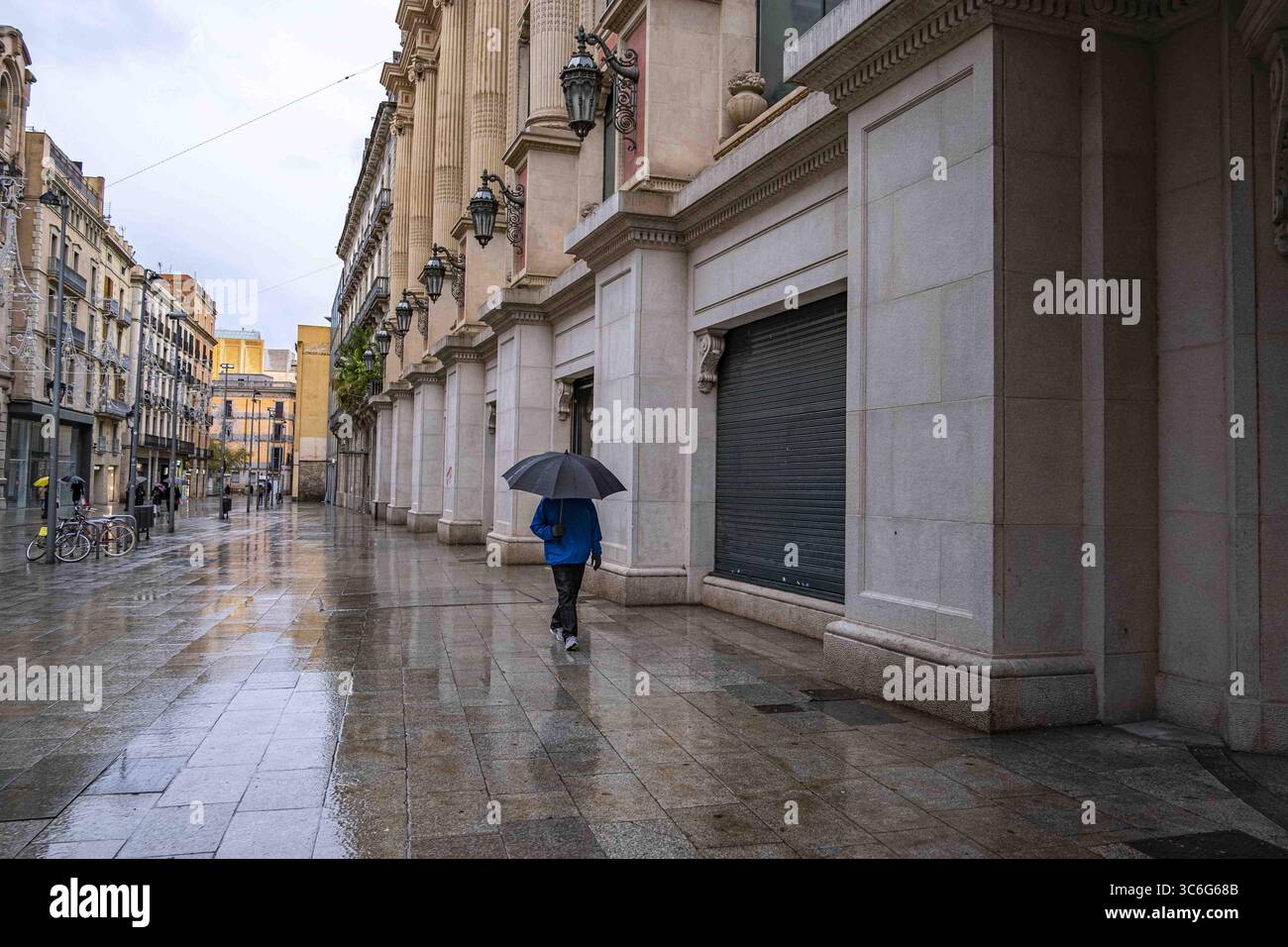 9 janvier 2021, Barcelone, Catalogne, Espagne : une femme un parapluie vu marcher devant les magasins fermés à travers la zone commerciale de Portal de l'Àngel..en raison d'une augmentation des infections au COVID-19, Barcelone souffre à nouveau d'un week-end avec des magasins non essentiels complètement fermés. (Crédit image : © Paco Freire/SOPA images via ZUMA Wire) Banque D'Images