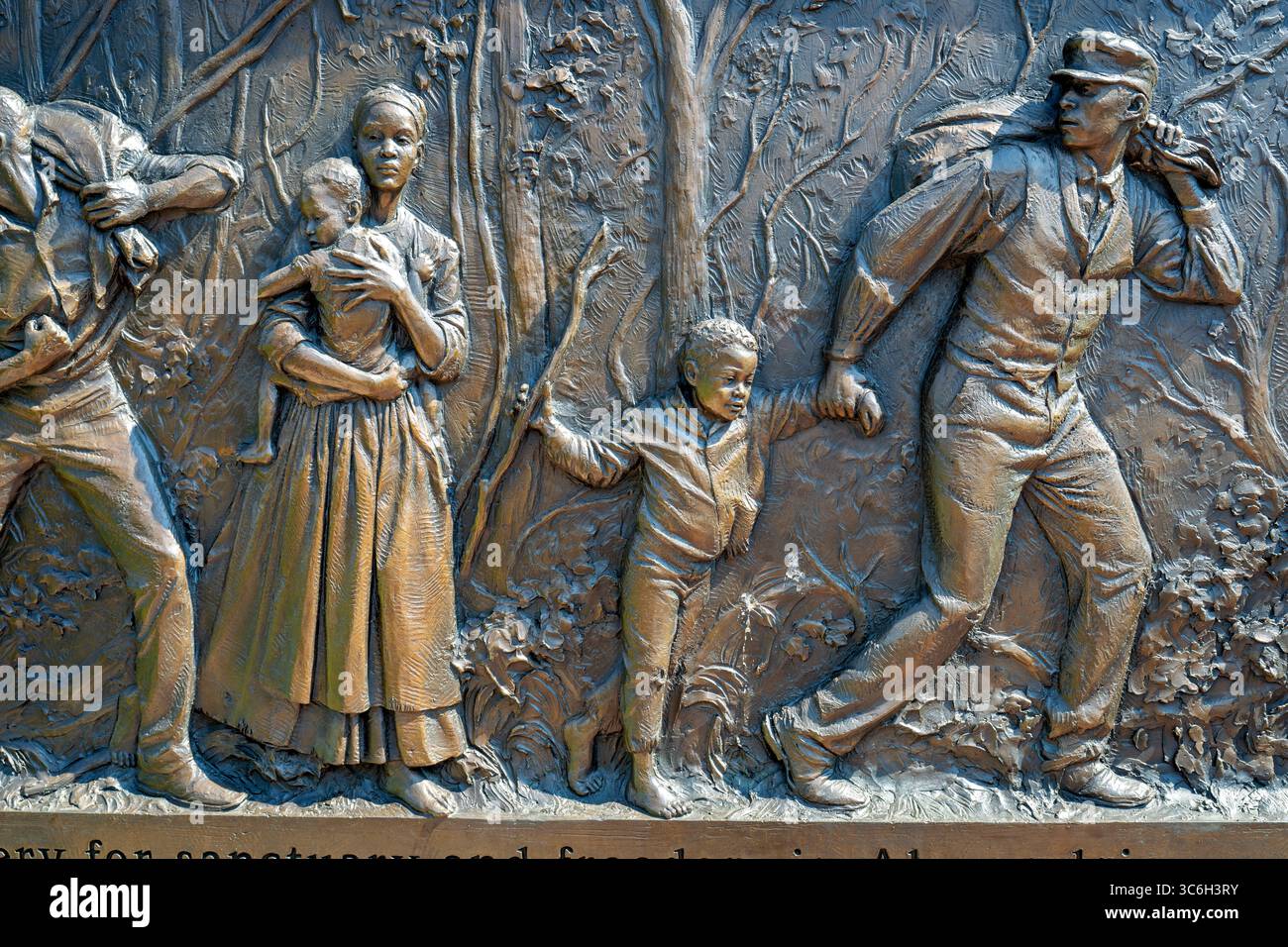 ALEXANDRIA, Virginie — Une sculpture en relief en bronze représente une famille fuyant l'esclavage au mémorial du cimetière des Contrabands et des Freedmen, avec l'inscription « fuir l'esclavage pour un sanctuaire et la liberté à Alexandrie ». L'œuvre du sculpteur local Joanna Blake fait partie du mémorial dédié en 2014 à 1 711 Afro-Américains morts entre 1864-1869 et enterrés dans le cimetière historique. Le cimetière est établi en mars 1864 sur des terres confédérées confisquées pour servir la communauté de contrebande et d'affranchis d'Alexandrie pendant la guerre de Sécession. Le site a acquis une importance nationale à Decemb Banque D'Images