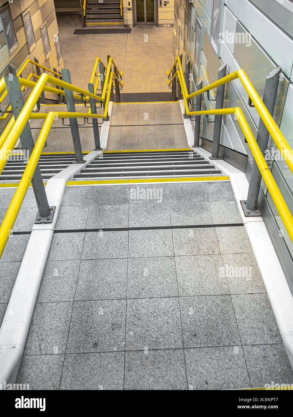 Dans un bâtiment contemporain, un élégant escalier moderne avec des garde-corps jaune vif mène élégamment vers le bas Banque D'Images
