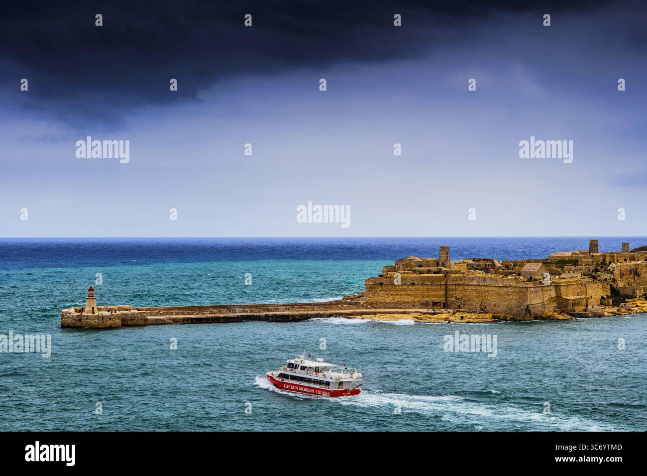 Ricasoli East Breakwater et Ricasoli Fort à Kalkara, Malte. Bateau de croisière Captain Morgan dans le Grand Harbour. Banque D'Images