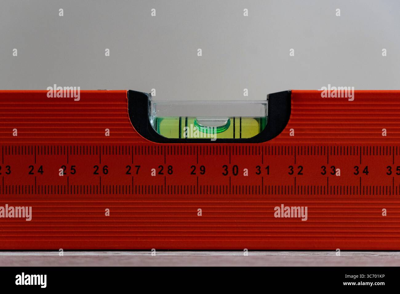Gros plan d'un outil de niveau à bulle rouge montrant une échelle de mesure et un flacon à bulles, idéal pour la construction, le bricolage, l'ingénierie, les thèmes du travail du bois Banque D'Images