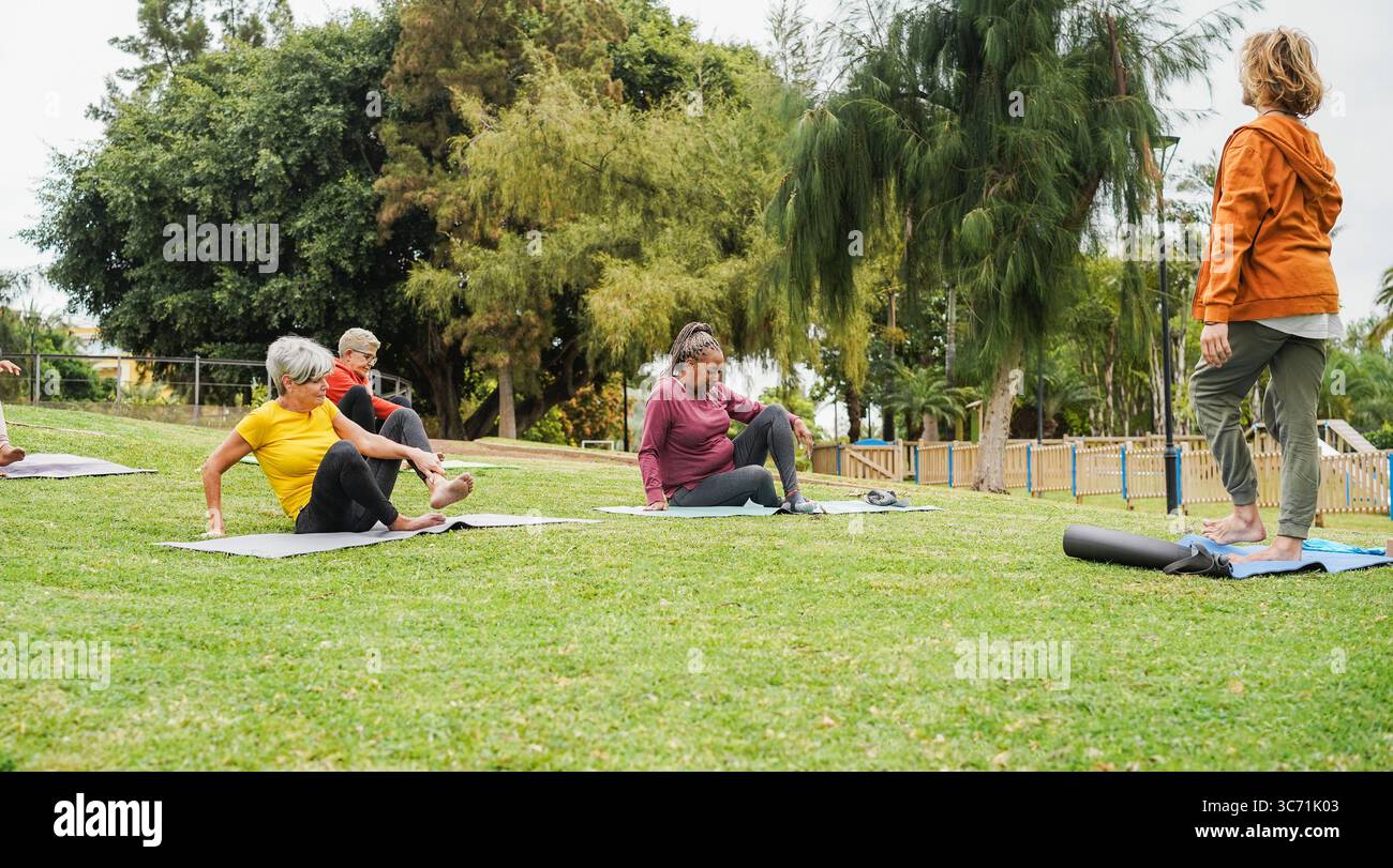 Groupe de personnes faisant des cours de yoga au parc de la ville - femmes multiraciales faisant de la méditation zen en plein air - concept de style de vie sain et spirituel Banque D'Images
