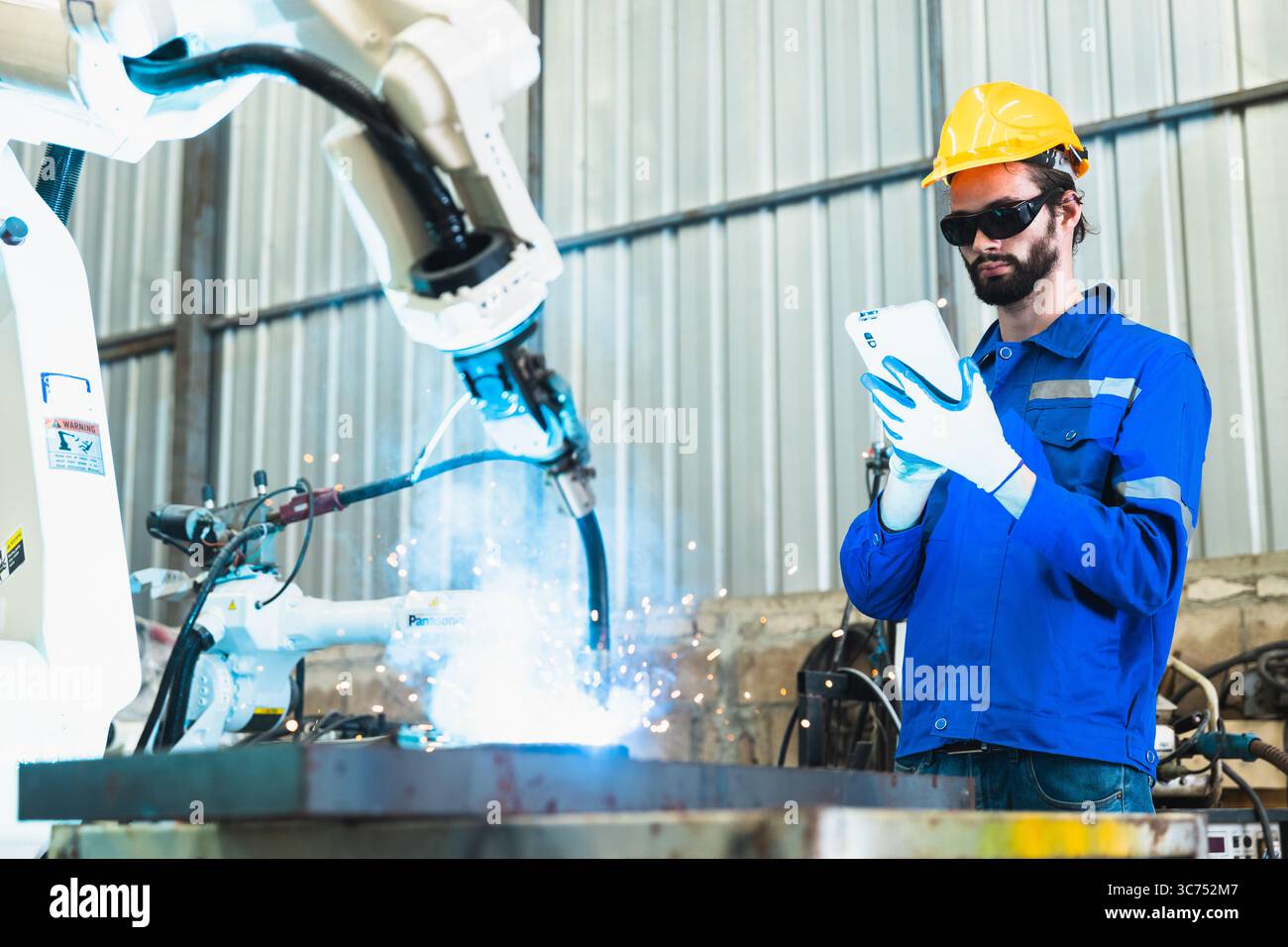 ingénieur robotique vérifiant un bras robotisé dans une usine industrielle Banque D'Images
