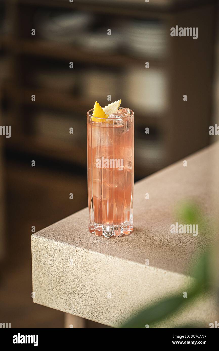 Cocktail rose avec glace et zeste de citron dans le verre Banque D'Images