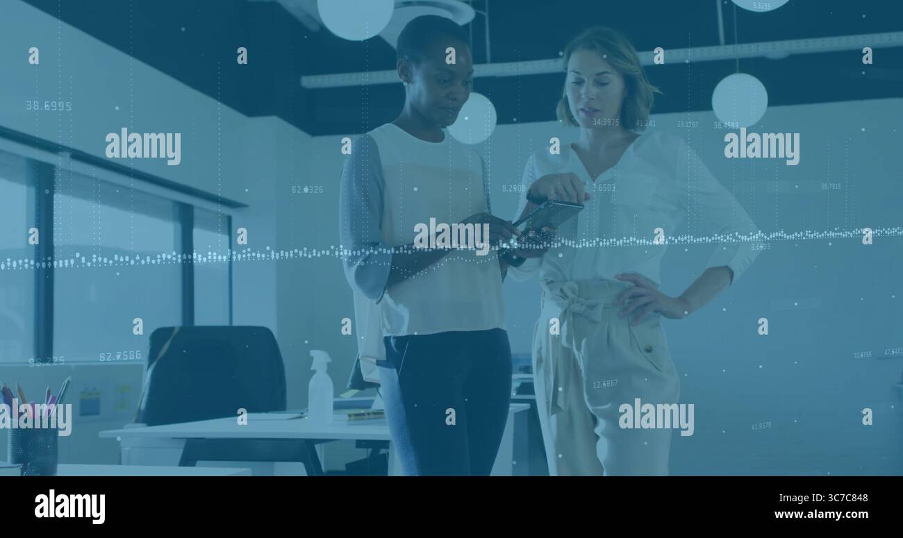 Discuter des femmes adultes moyens analysant l'écran de smartphone dans un bureau moderne, avec des superpositions de données numériques Banque D'Images