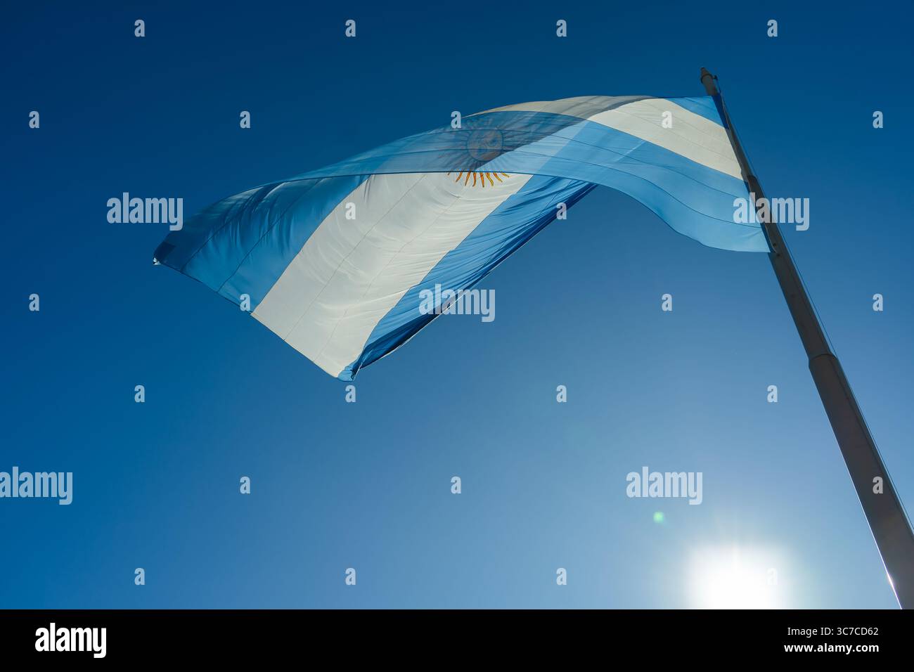 Le drapeau national de l'argentine agitant fièrement contre un ciel bleu clair, illuminé par la lumière du soleil Banque D'Images