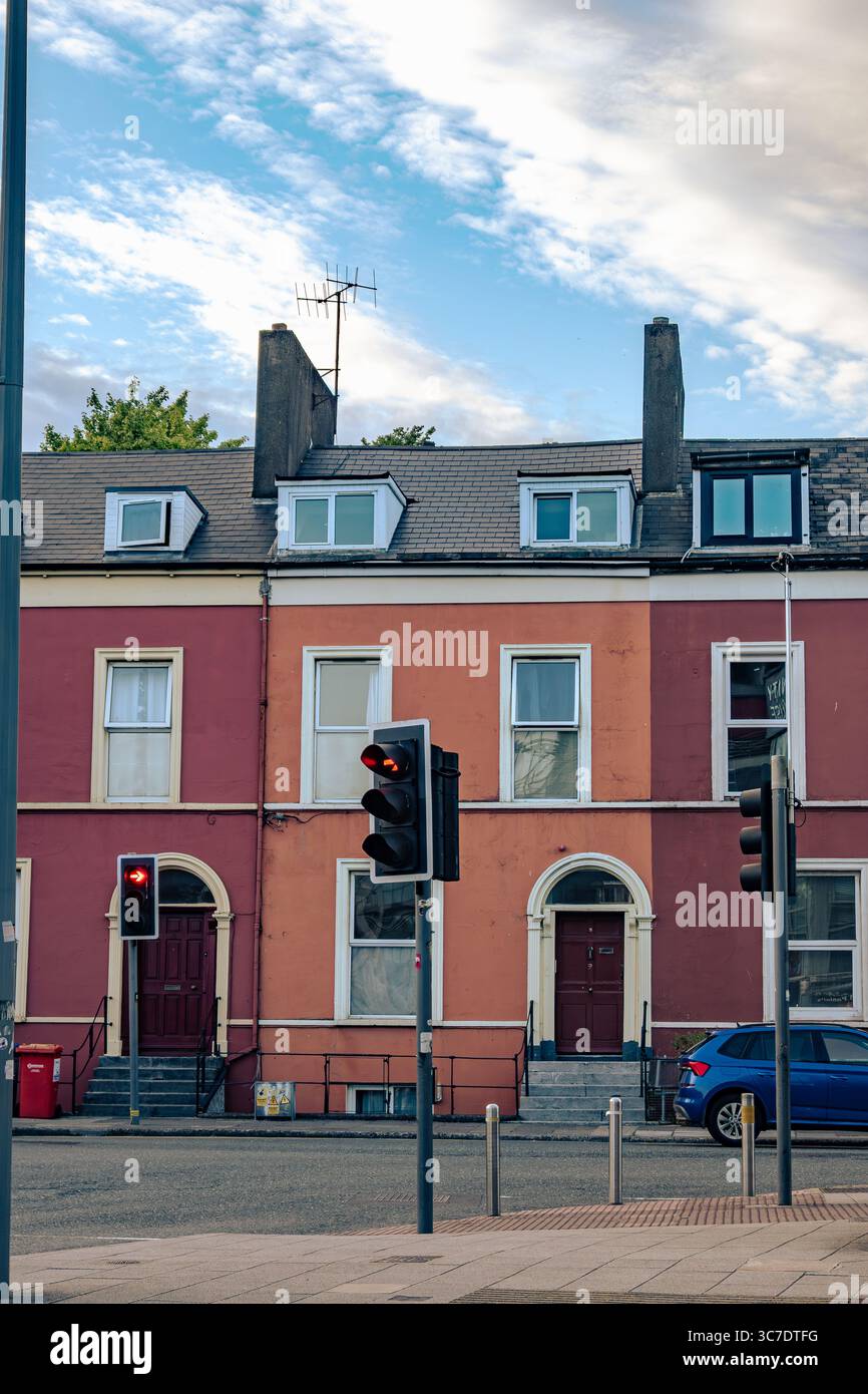 25 juillet 2025 Cork, Irlande Une voiture bleue est garée devant une longue rangée de maisons différentes Banque D'Images
