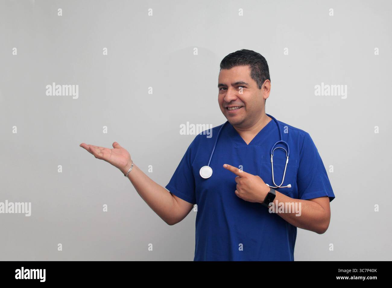 Médecin spécialiste latino-américain à la peau foncée avec un stéthoscope pointe avec son doigt avec une expression de joie et de surprise Banque D'Images Médecin spécialiste latino-américain à la peau foncée avec un stéthoscope pointe avec son doigt avec une expression de joie et de surprise Banque D'Images