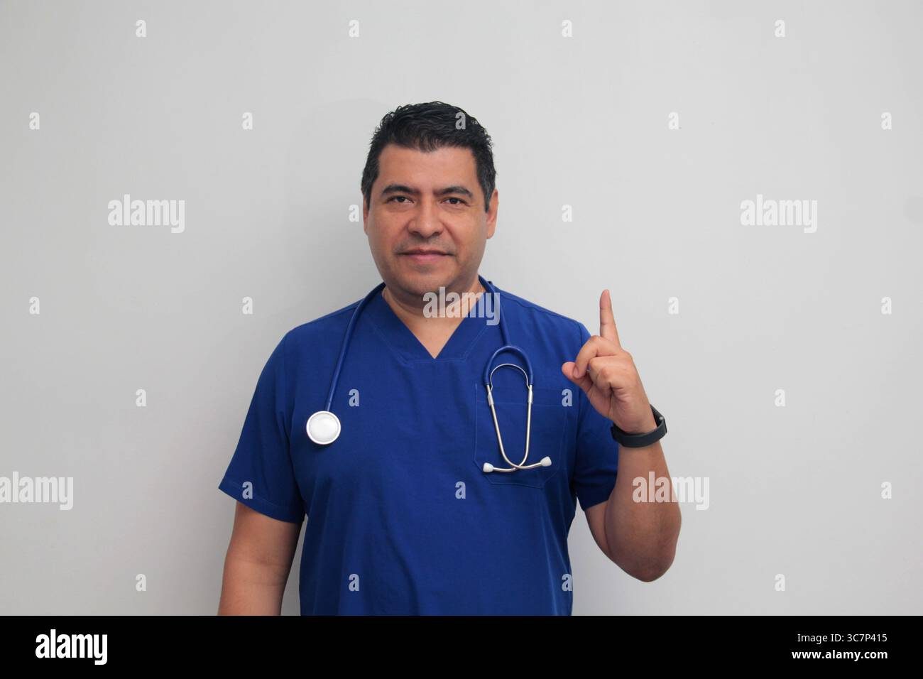 Médecin spécialiste latino-américain à la peau foncée avec un stéthoscope pointe avec son doigt avec une expression de joie et de surprise Banque D'Images Médecin spécialiste latino-américain à la peau foncée avec un stéthoscope pointe avec son doigt avec une expression de joie et de surprise Banque D'Images