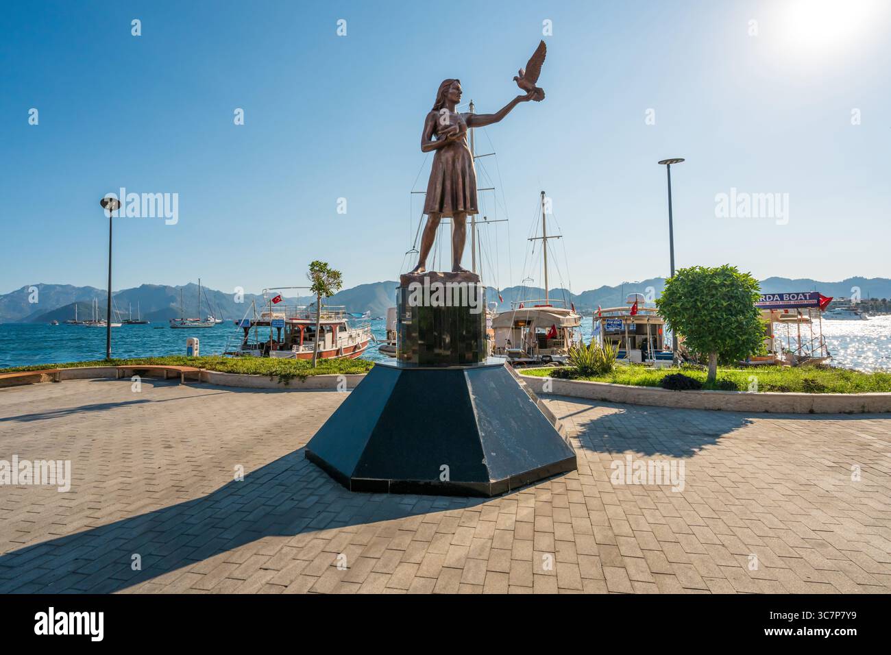 Marmaris, Turquie - 9 juillet 2025 : dame avec une statue de pigeon dans la marina de Marmaris avec des bateaux et la mer en arrière-plan Banque D'Images