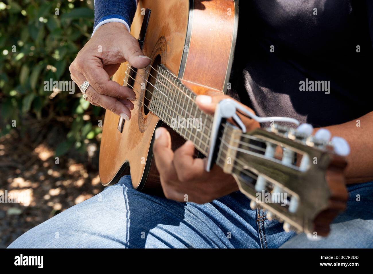 Gros plan détaillé des mains d'un guitariste jouant habilement des accords sur une guitare acoustique classique avec un Capo. Concentrez-vous sur les cordes, les touches et les musici Banque D'Images