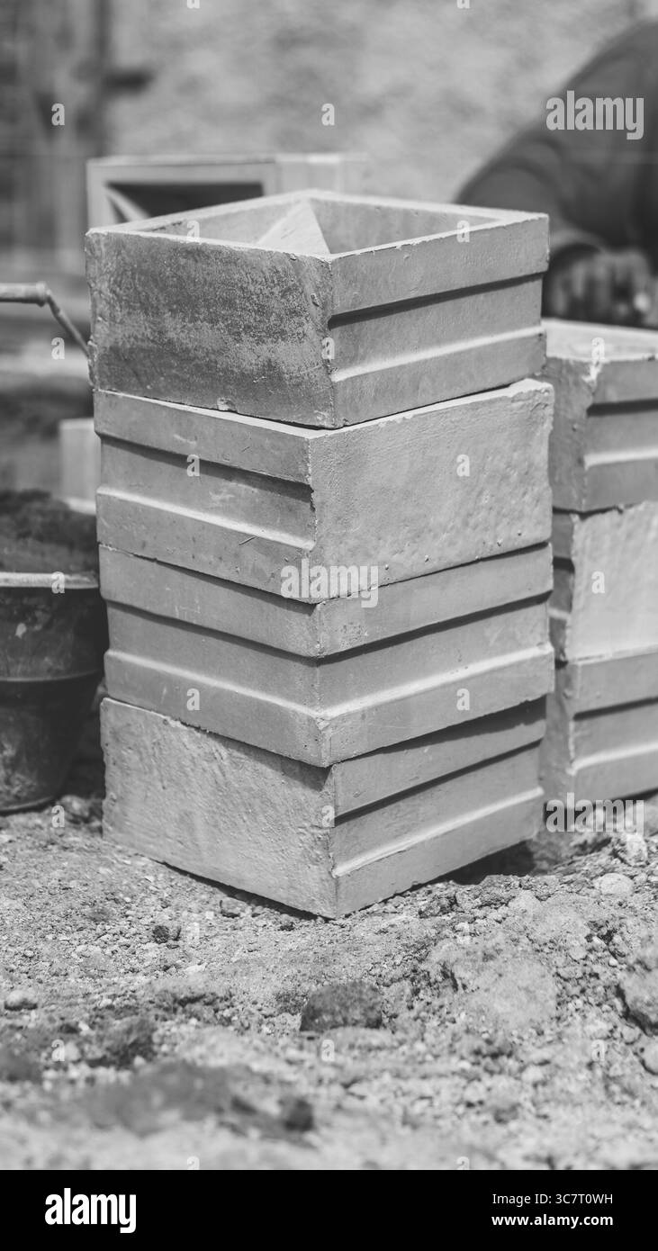 Un travailleur de la construction installe soigneusement des blocs de ventilation, créant des murs décoratifs qui améliorent la circulation de l'air et la conception architecturale. Banque D'Images