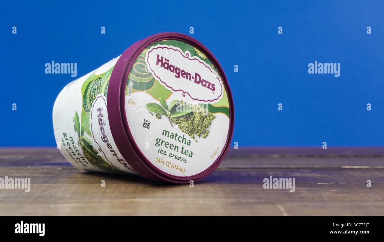 NORWALK, CT, États-Unis - 1er AOÛT 2025 : un contenant de crème glacée au thé vert matcha Haagen Dazs repose sur une surface en bois, incliné légèrement. Le bleu éclatant Banque D'Images