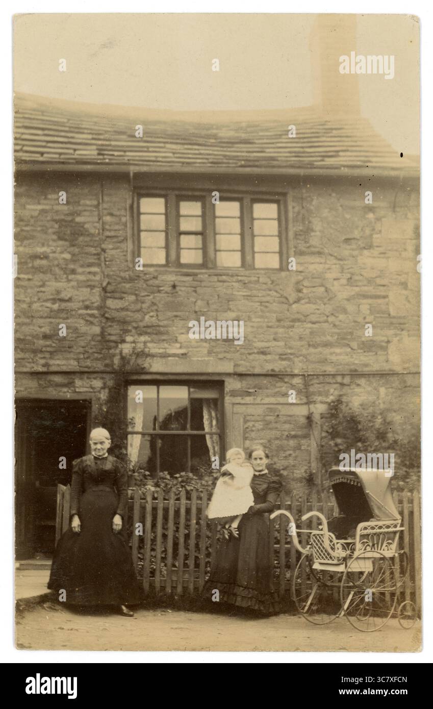 Carte postale de l'ère victorienne originale d'une grand-mère avec une mère et un bébé avec une poussette élaborée, debout à l'extérieur de leur maison victorienne / chalet de campagne. Circa 1902. ROYAUME-UNI Banque D'Images