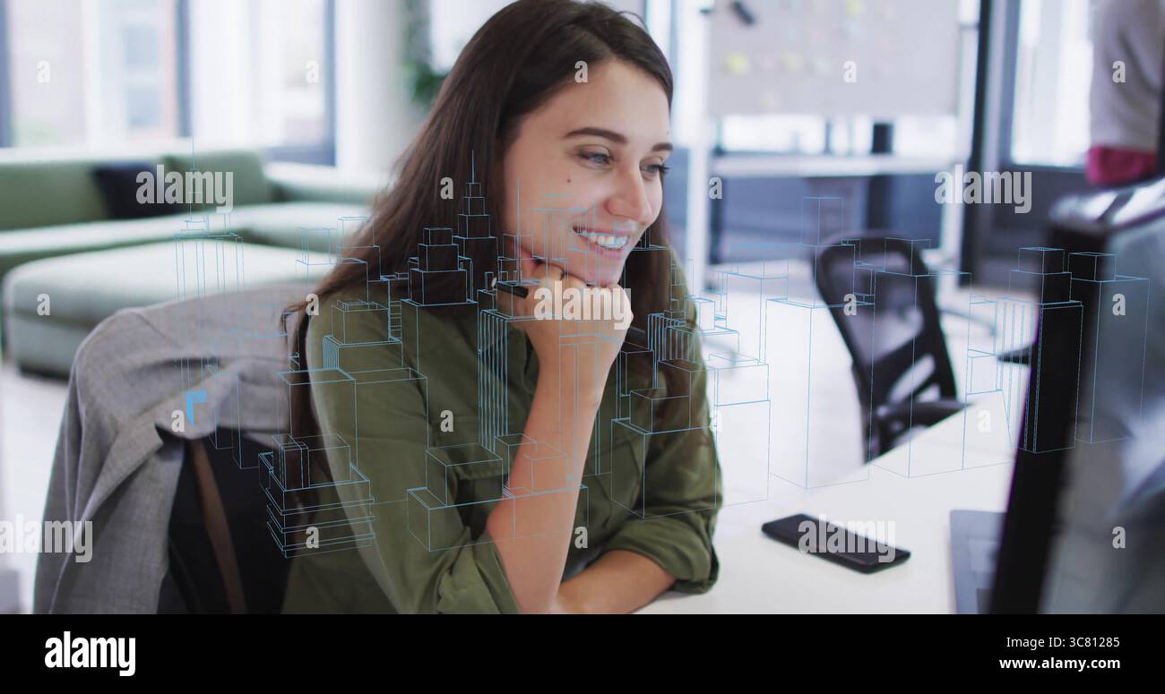 Femme souriante portant une chemise vert olive examinant le modèle de ville 3D sur le moniteur de bureau avec smartphone Banque D'Images