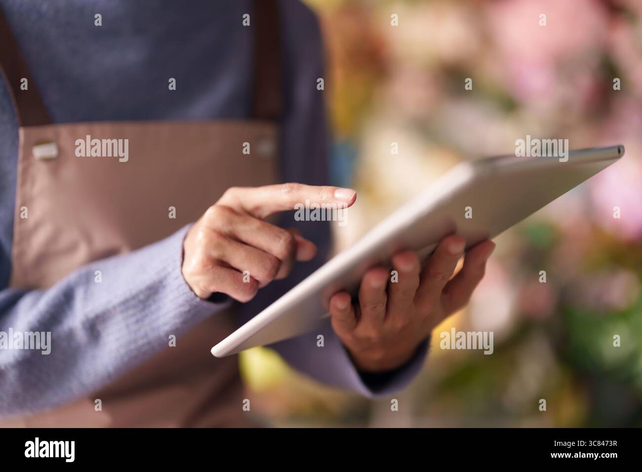 Fleuriste adulte utilise une tablette numérique pour gérer efficacement les commandes des clients de stock de fleuriste et rationaliser les opérations commerciales quotidiennes. Banque D'Images