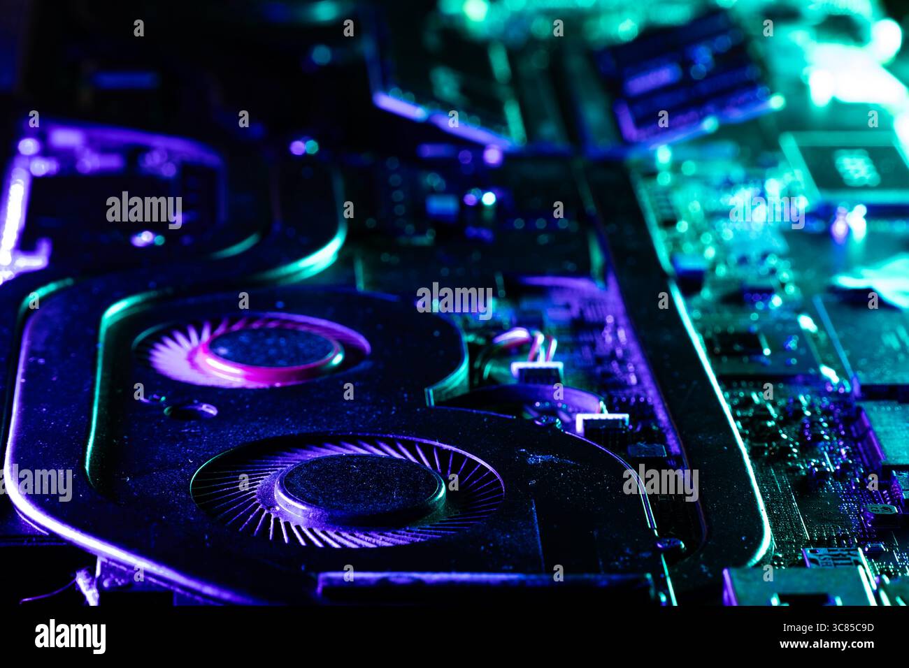 Gros plan d'un système de refroidissement GPU haute performance avec deux ventilateurs sous un éclairage bleu et vert spectaculaire Banque D'Images