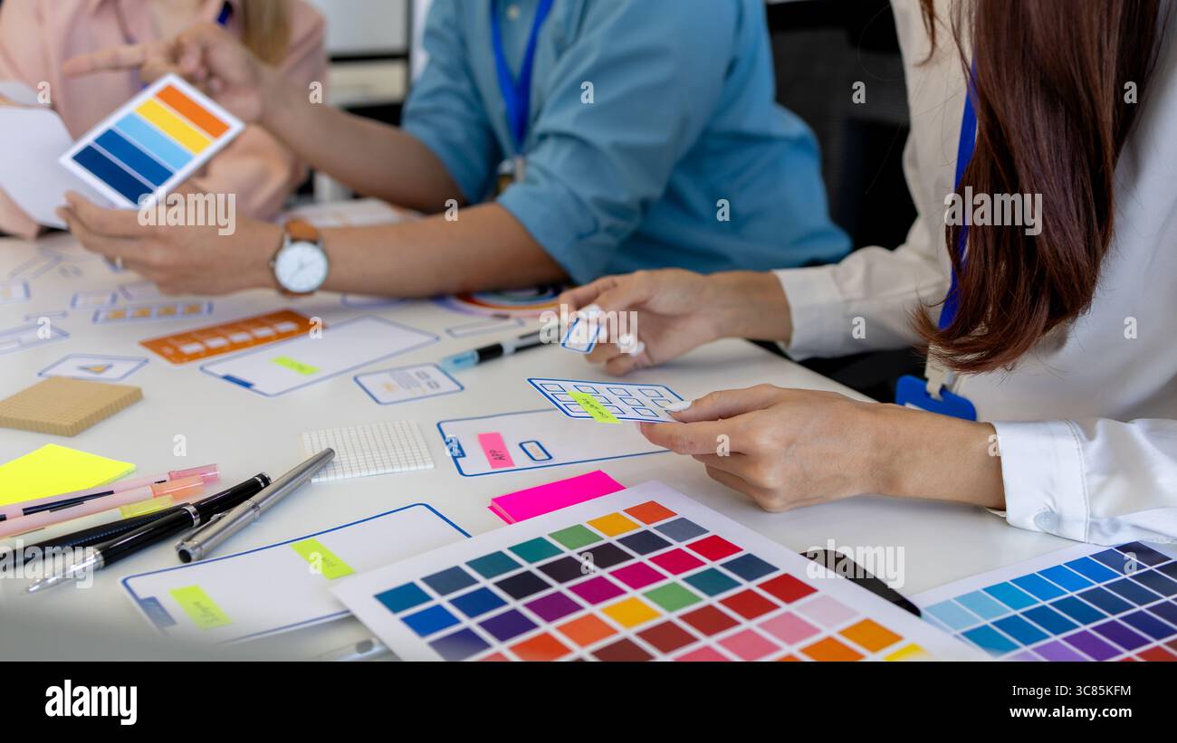 les concepteurs ux, ui, web et d'applications mobiles discutent de l'aspect et de la convivialité du site web ou de l'application qu'ils conçoivent, y compris des schémas de couleurs et des mises en page Banque D'Images