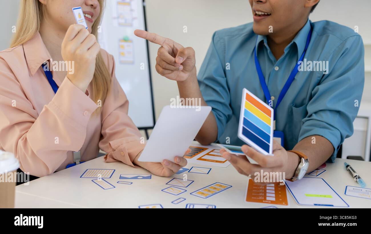 les concepteurs ux, ui, web et d'applications mobiles discutent de l'aspect et de la convivialité du site web ou de l'application qu'ils conçoivent, y compris des schémas de couleurs et des mises en page Banque D'Images