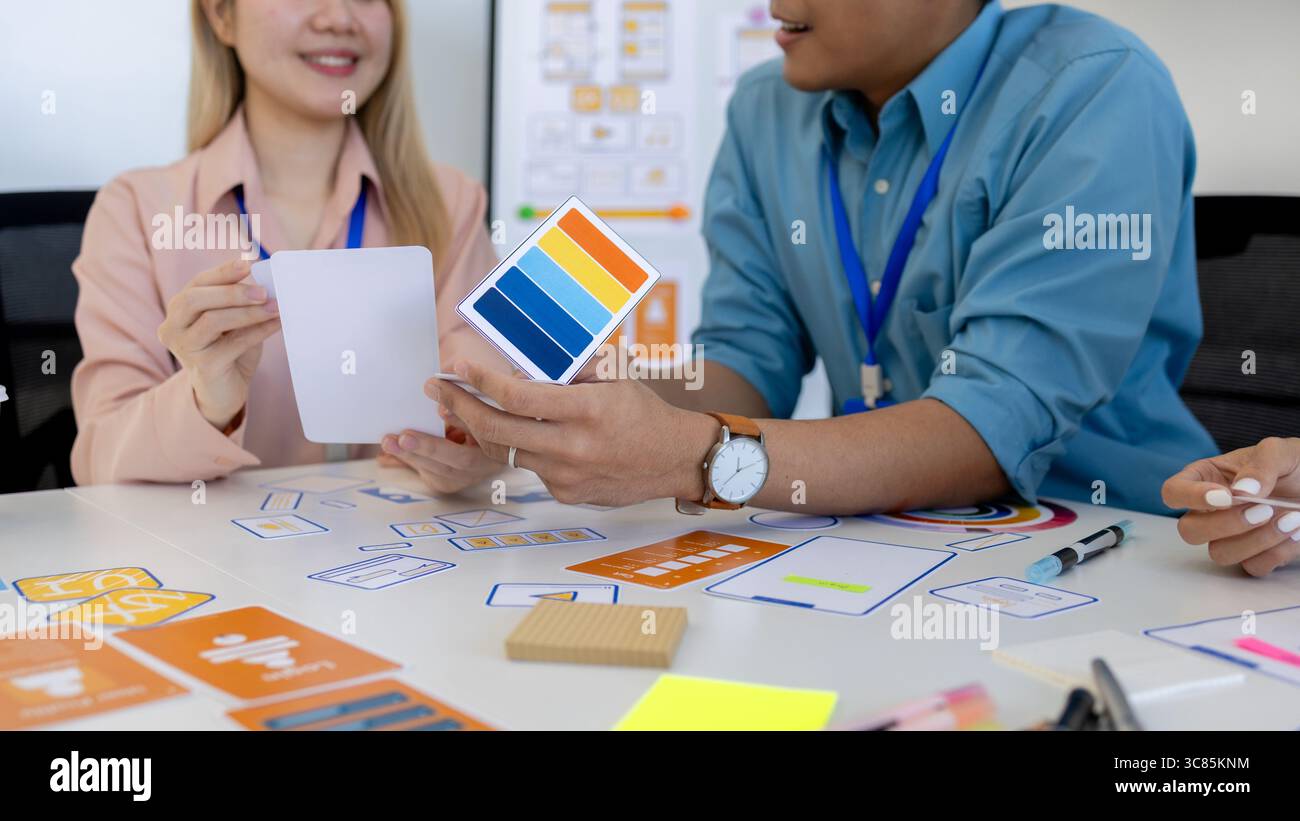 les concepteurs ux, ui, web et d'applications mobiles discutent de l'aspect et de la convivialité du site web ou de l'application qu'ils conçoivent, y compris des schémas de couleurs et des mises en page Banque D'Images