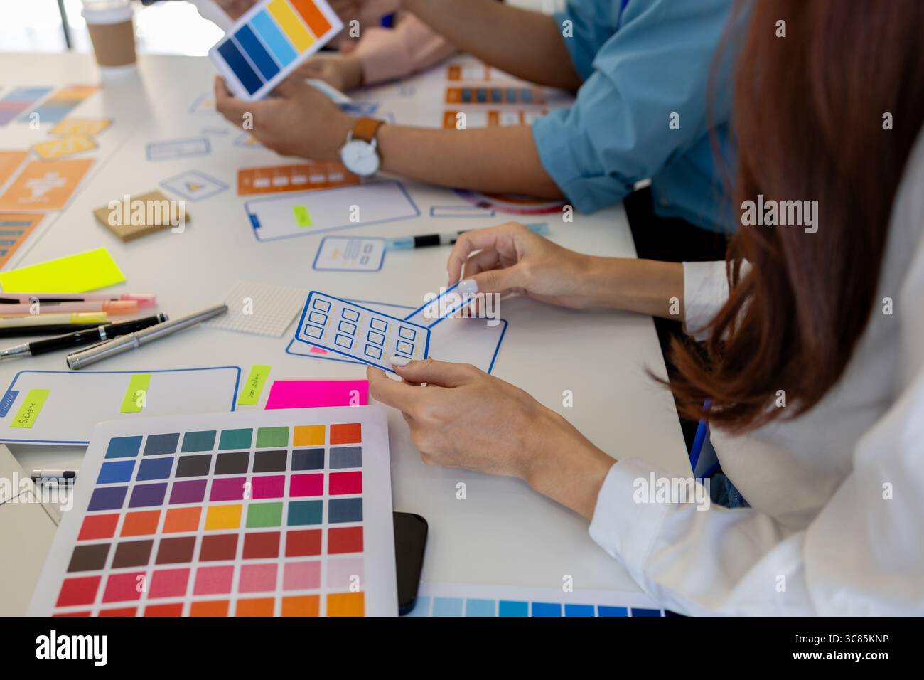 les concepteurs ux, ui, web et d'applications mobiles discutent de l'aspect et de la convivialité du site web ou de l'application qu'ils conçoivent, y compris des schémas de couleurs et des mises en page Banque D'Images