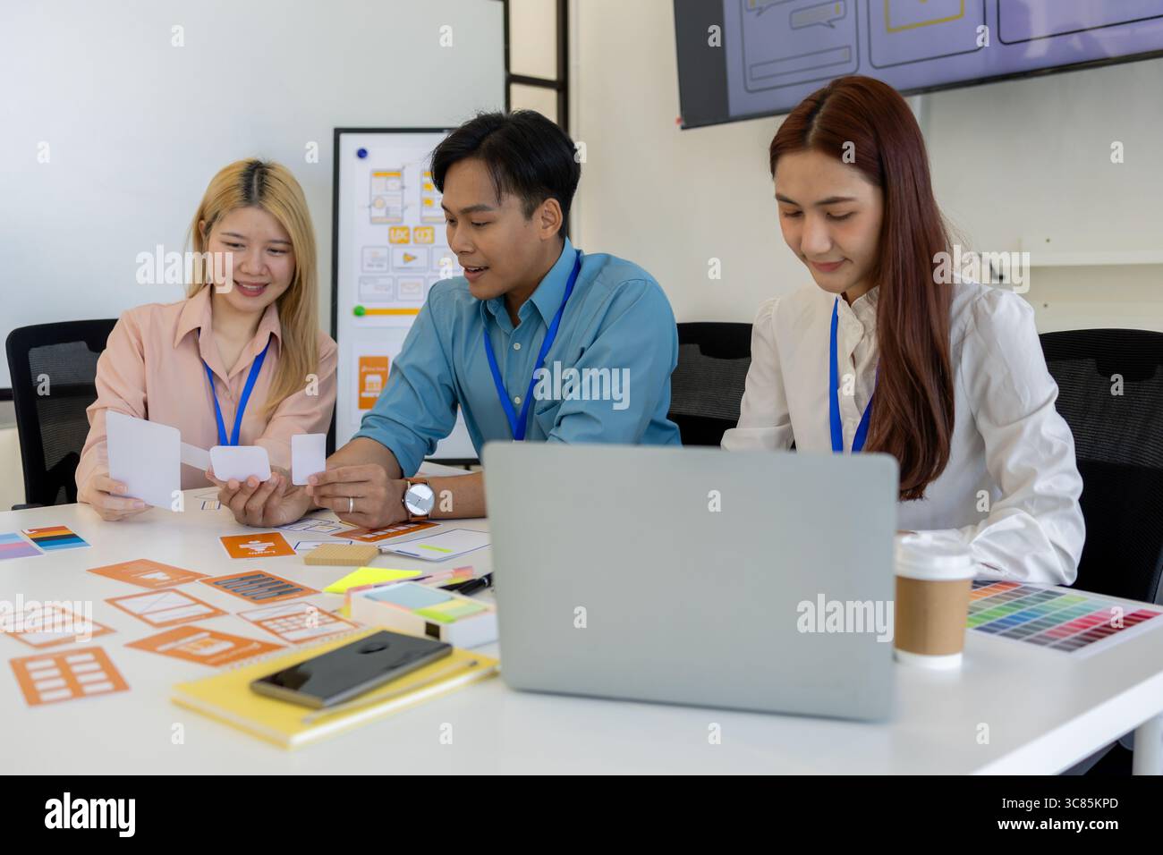 les concepteurs ux, ui, web et d'applications mobiles discutent de l'aspect et de la convivialité du site web ou de l'application qu'ils conçoivent, y compris des schémas de couleurs et des mises en page Banque D'Images