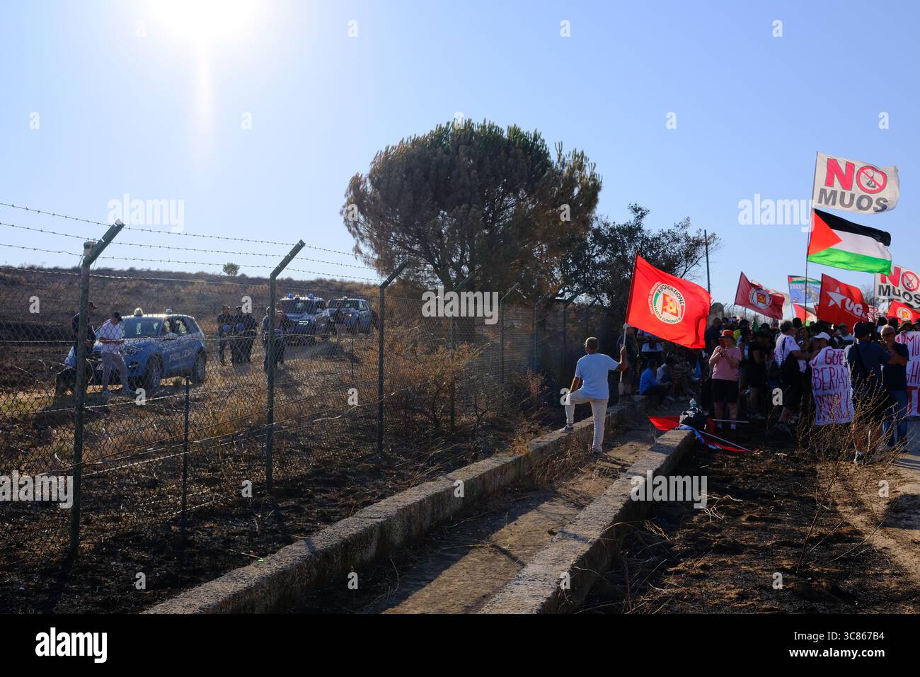 Niscemi, Sicile – 2 août 2025. Manifestation contre le système de communication par satellite MUOS militaire américain basé à l'intérieur de la réserve naturelle de Sughereta à Niscemi. Des centaines de militants du No MUOS se sont rassemblés près du site pour protester contre la présence continue de l'infrastructure militaire américaine sur le territoire sicilien. La manifestation a comporté des discours et une Assemblée en plein air où les participants se sont assis sur la route pour écouter et discuter des propositions. Une forte présence des jeunes et plusieurs organisations environnementales et pacifistes y ont participé. Crédit : Alessio Tricani/Alamy Live News Banque D'Images