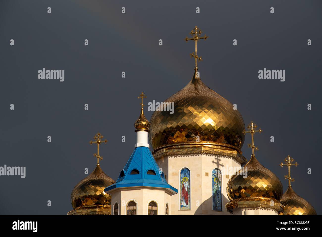 Les dômes dorés et les croix d'une église orthodoxe brillent brillamment contre un ciel orageux Banque D'Images