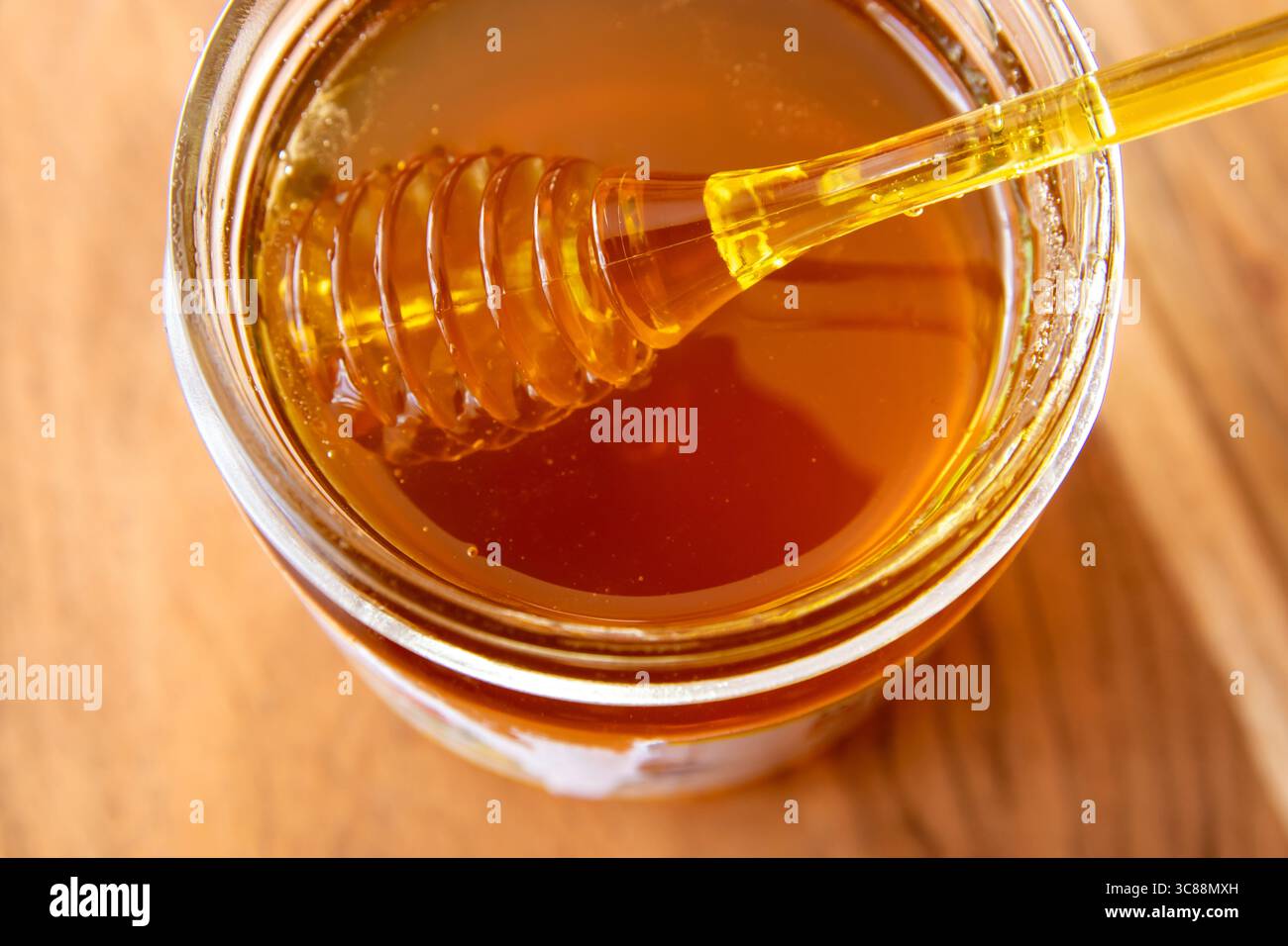 Pot en verre de miel avec nid d'abeilles et cuillère jaune rester sur la table en bois. Banque D'Images