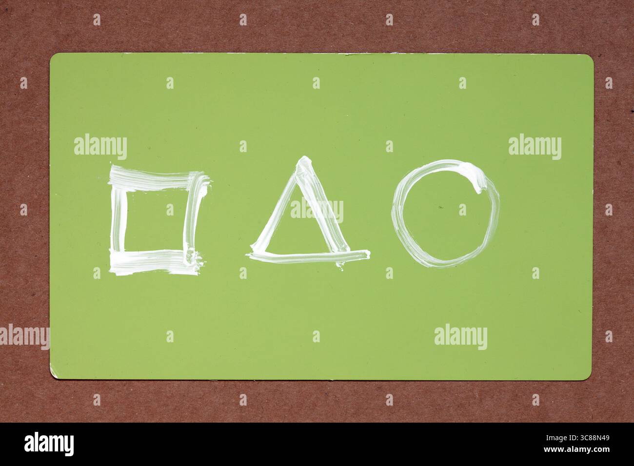 design minimaliste avec trois formes géométriques blanches : carré, triangle et cercle disposés horizontalement sur un fond rectangulaire vert clair Banque D'Images