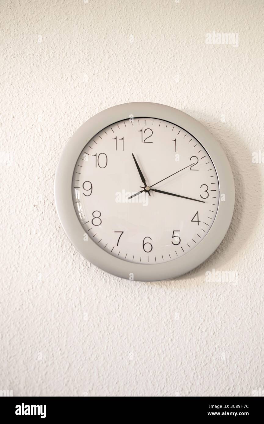 Une horloge murale sur un mur blanc Banque D'Images